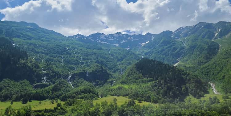 A green Alpine valley beneath rocky mountain summits
